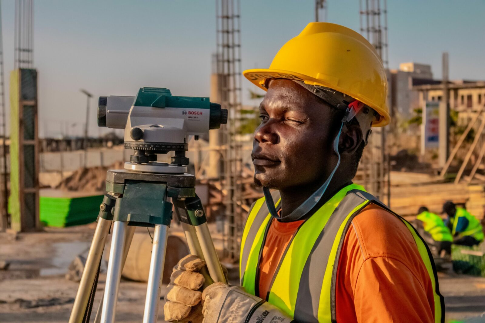 A surveyor stands with equipment at a city intersection, capturing urban measurements.